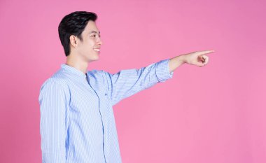 Pembe arka planda genç Asyalı bir adamın portresi