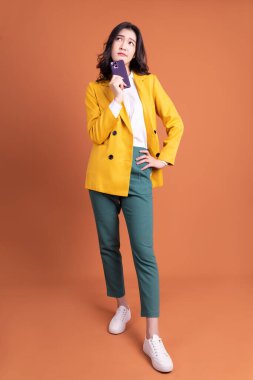 Arka planda akıllı telefon kullanan genç Asyalı kadının tam boy görüntüsü