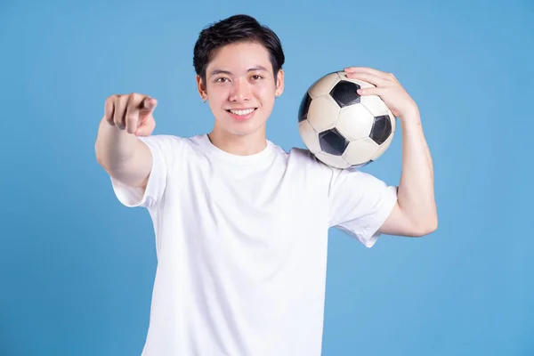 stock image Young Asian man holding ball on background