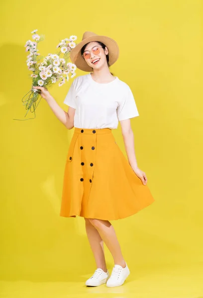 stock image Full length photo of young Asian woman holding flower on yellow background