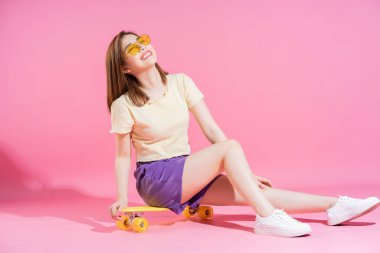 Pembe arka planda kaykaylı Asyalı genç kızın fotoğrafı.