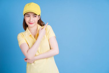 Mavi arka planda genç bir Asyalı teslimatçı kadın resmi