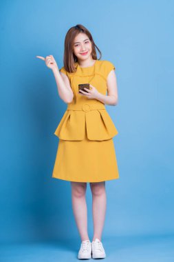 Mavi arka planda genç Asyalı iş kadınının tam boy fotoğrafı.