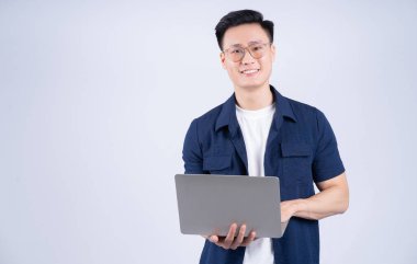 Beyaz arka planda dizüstü bilgisayar kullanan genç bir Asyalı.