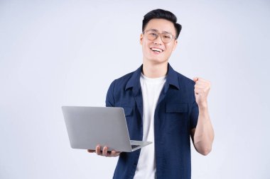 Beyaz arka planda dizüstü bilgisayar kullanan genç bir Asyalı.