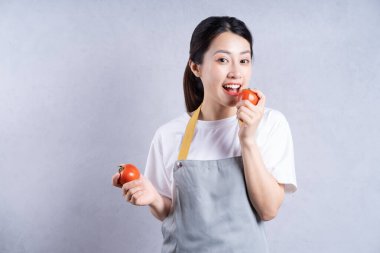 Arka planda sebze tutan genç Asyalı kadın.