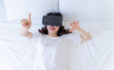Genç Asyalı kadın evde sanal gerçeklik gözlüğü kullanıyor.