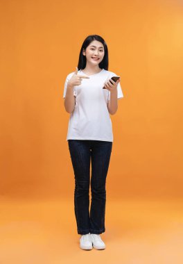 Genç Asyalı kız arka planda akıllı telefon kullanıyor.