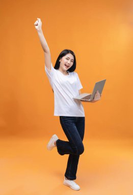 Genç Asyalı kız arka planda dizüstü bilgisayar kullanıyor.