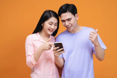 Arka planda akıllı telefon kullanan genç Asyalı çift