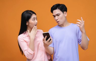 Arka planda akıllı telefon kullanan genç Asyalı çift