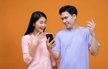 Arka planda akıllı telefon kullanan genç Asyalı çift