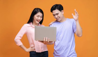 Arka planda dizüstü bilgisayar kullanan genç Asyalı çift