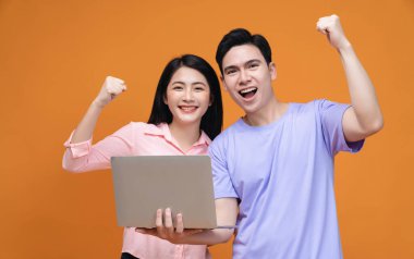 Arka planda dizüstü bilgisayar kullanan genç Asyalı çift