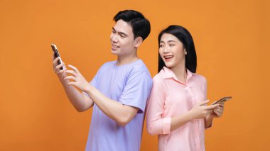 Arka planda akıllı telefon kullanan genç Asyalı çift