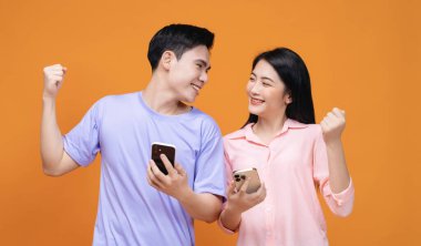 Arka planda akıllı telefon kullanan genç Asyalı çift