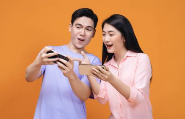 Arka planda akıllı telefon kullanan genç Asyalı çift