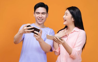 Arka planda akıllı telefon kullanan genç Asyalı çift