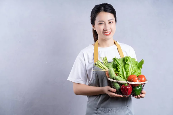 stock image Young Asian woman holding vegetables on background