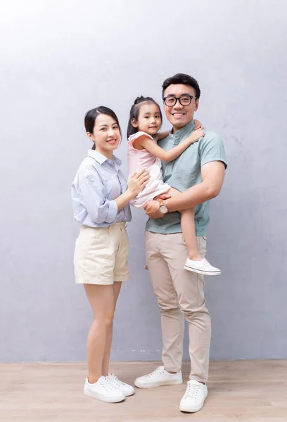 Young Asian family standing on background