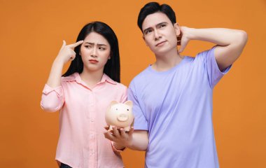 Arka planda domuz kumbarası tutan genç Asyalı çift.