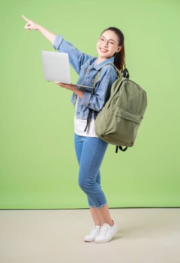 Yeşil arka planda genç bir Asyalı üniversiteli kızın fotoğrafı
