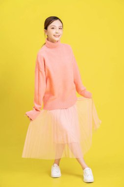 Sarı arka planda genç bir Asyalı kızın fotoğrafı