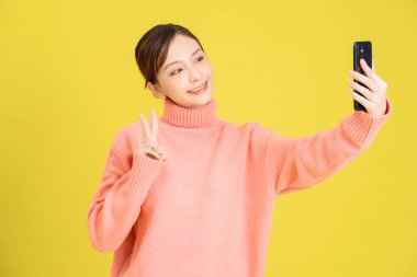 Arka planda akıllı telefon kullanan Asyalı genç bir kız görüntüsü