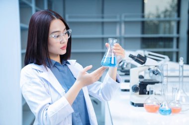 Laboratuvarda çalışan Asyalı genç bir kadının resmi.