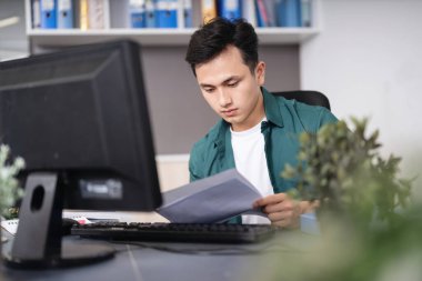 Ofiste çalışan genç Asyalı iş adamının fotoğrafı.