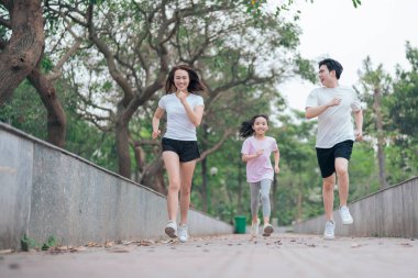 Park 'taki genç Asyalı aile egzersizinin fotoğrafı.