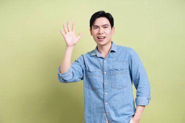 Yeşil arka plandaki genç Asyalı adamın fotoğrafı.