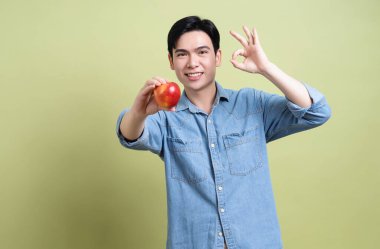 Yeşil arka plandaki genç Asyalı adamın fotoğrafı.