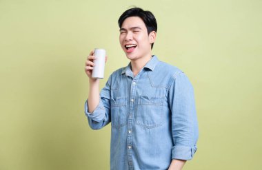 Yeşil arka plandaki genç Asyalı adamın fotoğrafı.