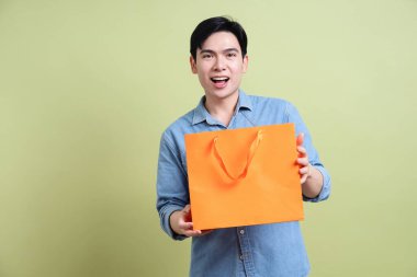 Yeşil arka plandaki genç Asyalı adamın fotoğrafı.