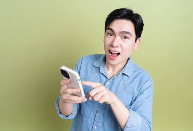 Yeşil arka plandaki genç Asyalı adamın fotoğrafı.