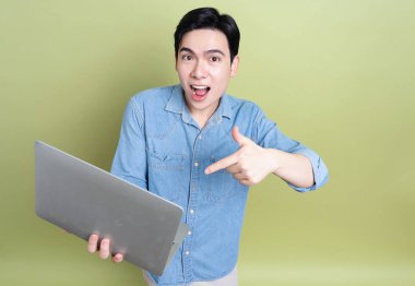 Yeşil arka plandaki genç Asyalı adamın fotoğrafı.