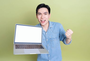 Yeşil arka plandaki genç Asyalı adamın fotoğrafı.