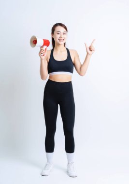 Beyaz arka planda spor giyimli genç Asyalı kadın.