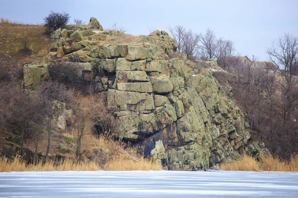凍結した川や湖の岸に岩 花崗岩の露頭を持つ冬の川の銀行 — ストック写真