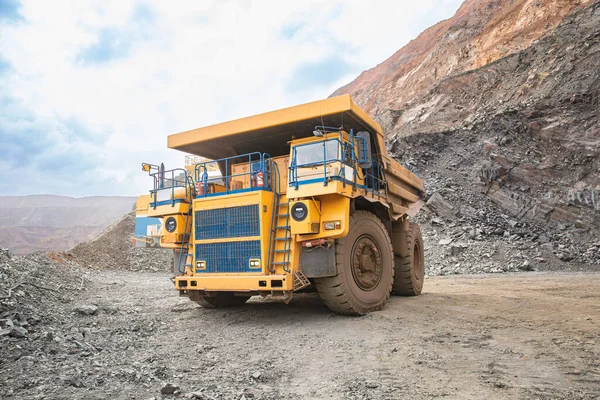 Large yellow open-pit dump truck in an open-pit mining operation. Ore mining equipment and machinery.