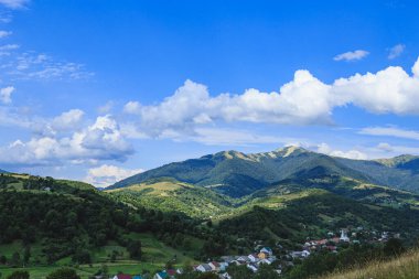 Dağlar dağ köyünün ovalarında ormanlarla kaplıdır. Güneşli bir günde bulutlarla kaplı kırsal dağlar..