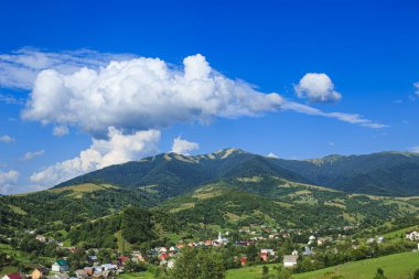 Dağlar dağ köyünün ovalarında ormanlarla kaplıdır. Güneşli bir günde bulutlarla kaplı kırsal dağlar..