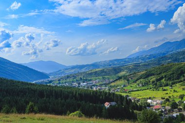 Dağlar dağ köyünün ovalarında ormanlarla kaplıdır. Güneşli bir günde bulutlarla kaplı kırsal dağlar..