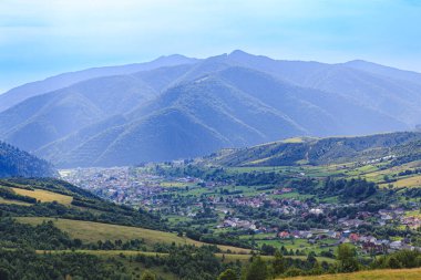 Dağlar dağ köyünün ovalarında ormanlarla kaplıdır. Güneşli bir günde bulutlarla kaplı kırsal dağlar..