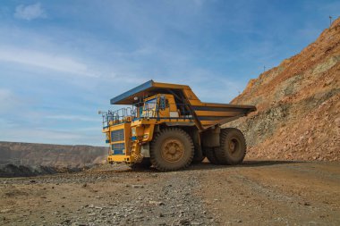 Large dump truck for removal of rock mass from the quarry for open-pit mining of minerals. Initial stage of metallurgy, machinery for the extraction of raw ore.