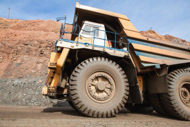 Large dump truck for removal of rock mass from the quarry for open-pit mining of minerals. Initial stage of metallurgy, machinery for the extraction of raw ore.