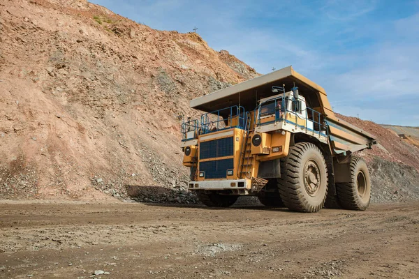 Large dump truck for removal of rock mass from the quarry for open-pit mining of minerals. Initial stage of metallurgy, machinery for the extraction of raw ore.