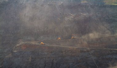 Large yellow dump trucks engaged in the transportation of rock mass in the quarry for mining. Machinery and equipment for iron ore mining