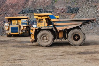 Large yellow dump trucks engaged in the transportation of rock mass in the quarry for mining. Machinery and equipment for iron ore mining